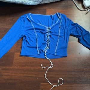 Blue long sleeve crop top with slit in the middle and drawstring detail.